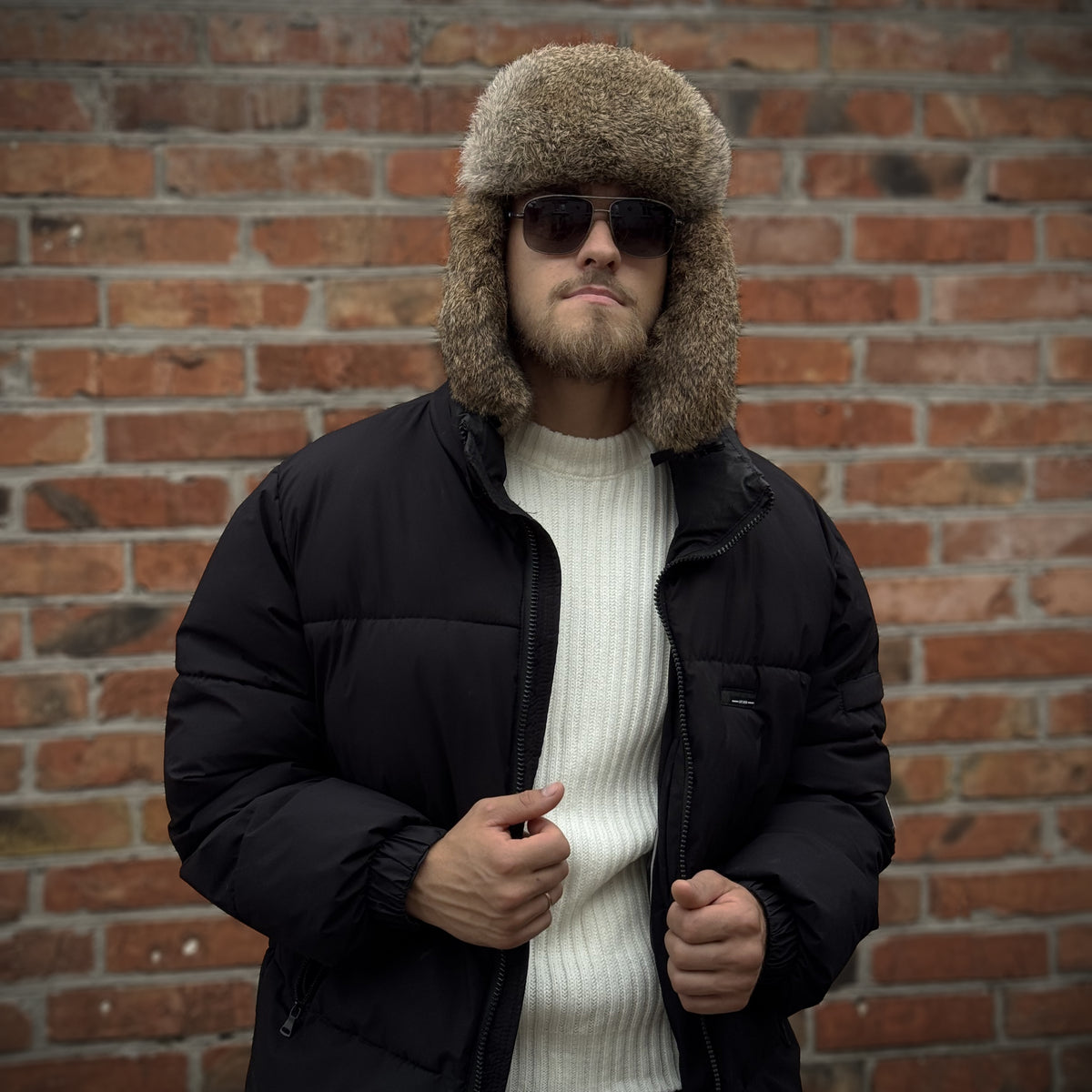 Men's black rabbit fur ushanka hat worn with ear flaps down in winter style